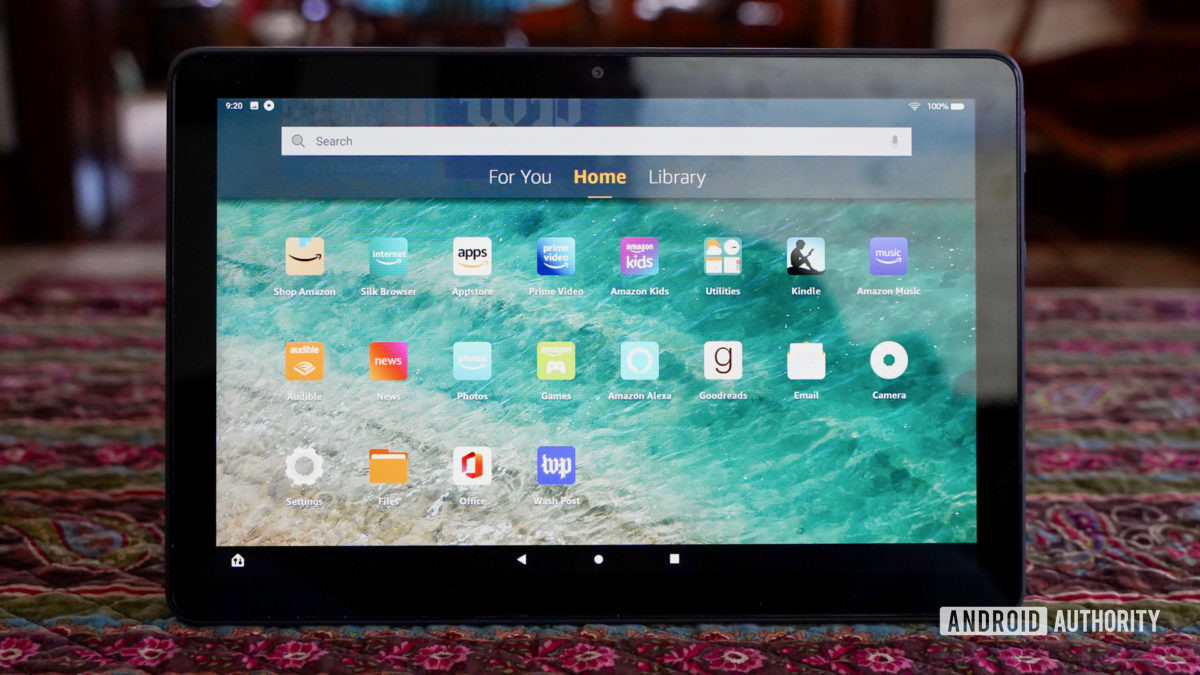 The Amazon Fire HD 10 Plus on a coffee table showing the home screen with apps.