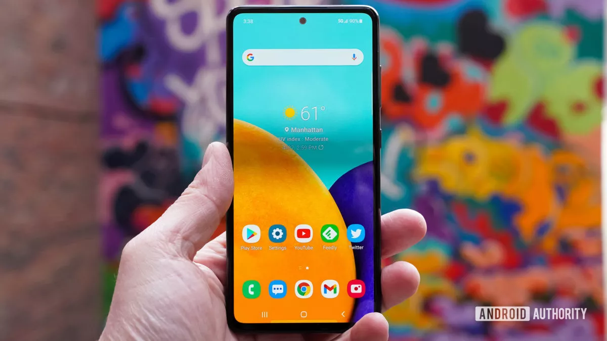 Samsung Galaxy A52 5G in hand showing the home screen and apps.