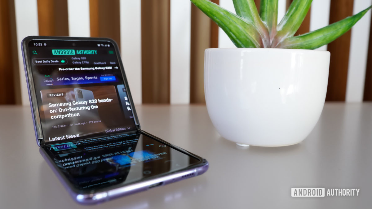 The Samsung Galaxy Z Flip leaning back resting on a table next to a plant in a pot.