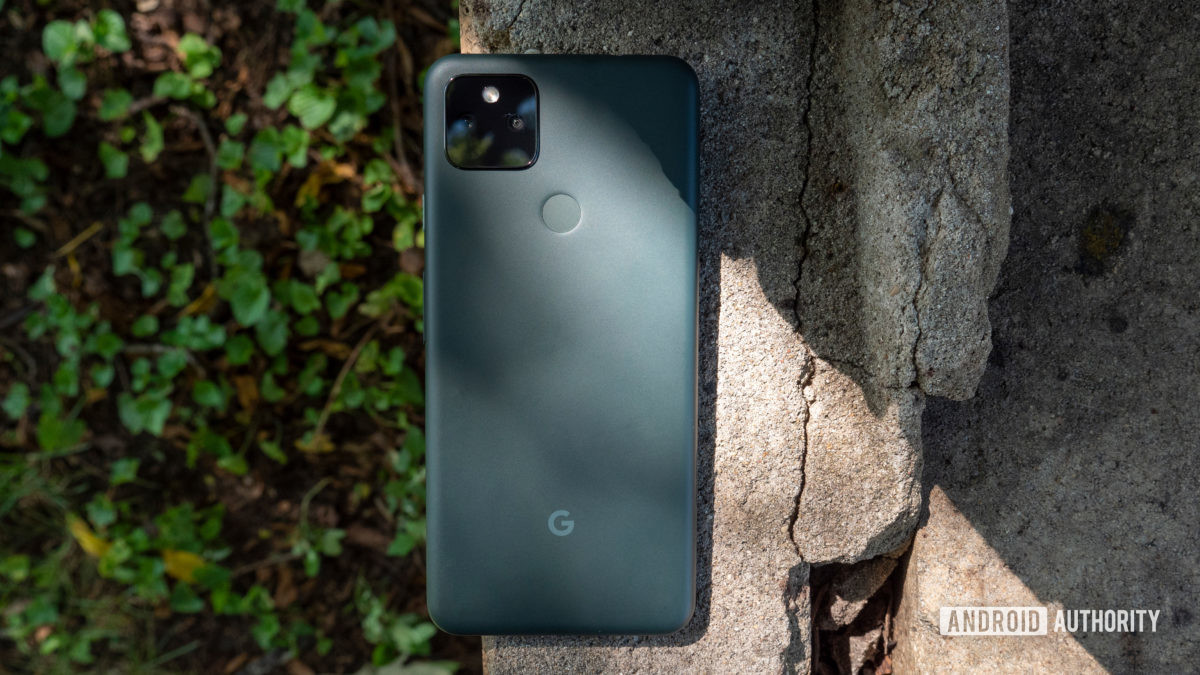 the google pixel 5a on a piece of cement showing its back in mostly black color