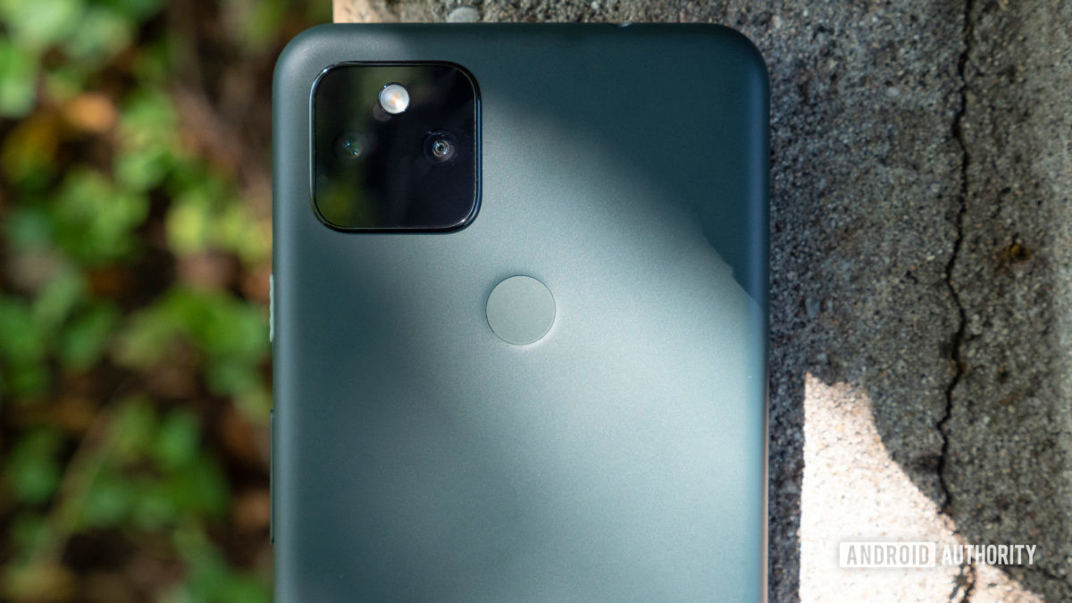 the google pixel 5a on a piece of cement showing its back in mostly black color with a camera close up