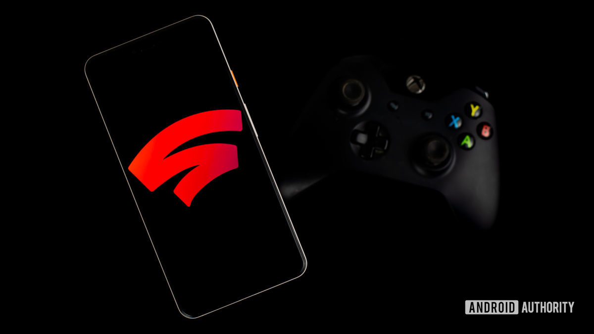 Google Stadia on smartphone next to gaming controller stock photo 1