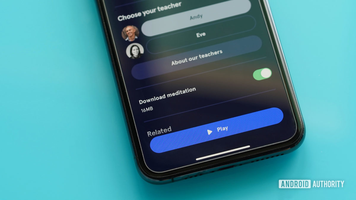 An iPhone 11 on a teal table displays how to download Headspace content for offline listening.