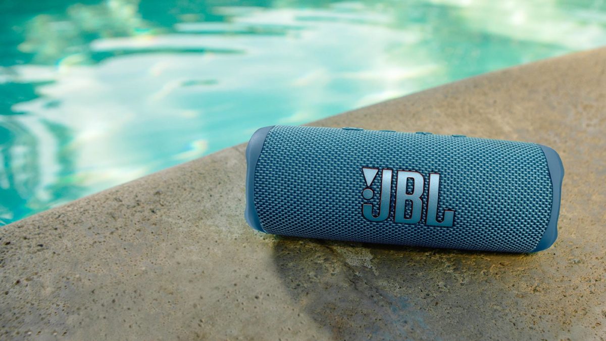 The JBL Flip 6 in blue rests poolside.