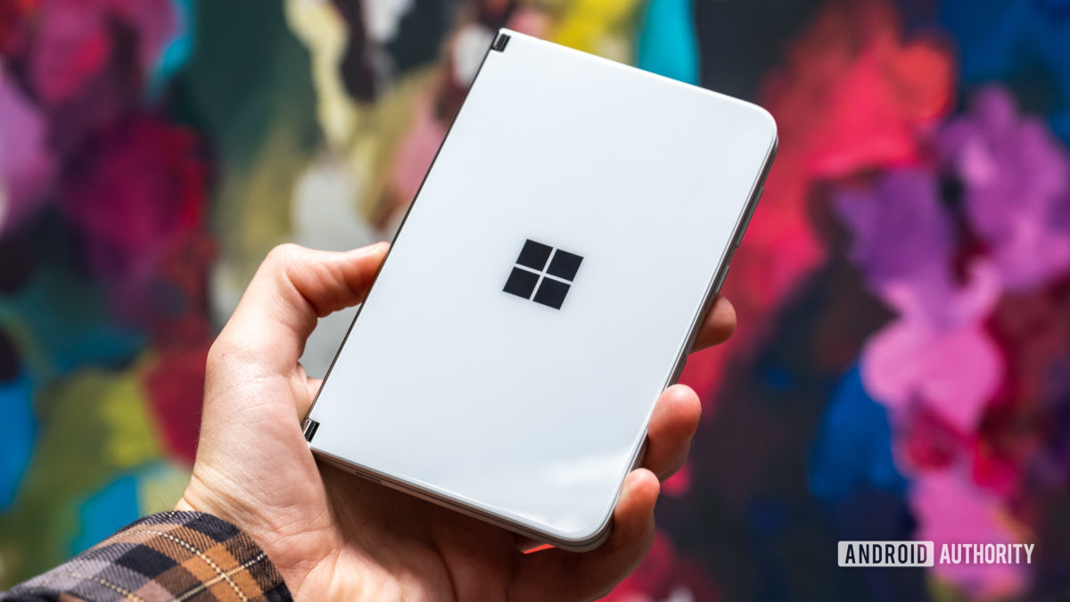 Microsoft Surface Duo closed in hand against backdrop