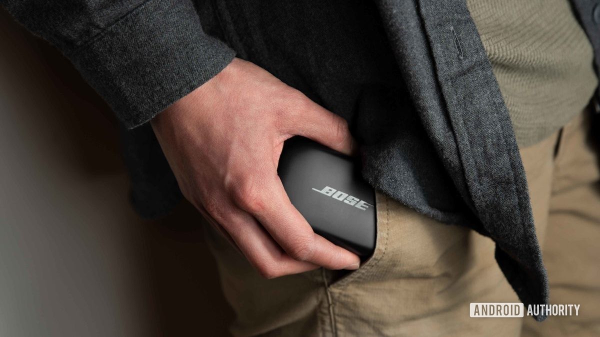 A woman removes the Bose QuietComfort Earbuds case from a pants pocket.