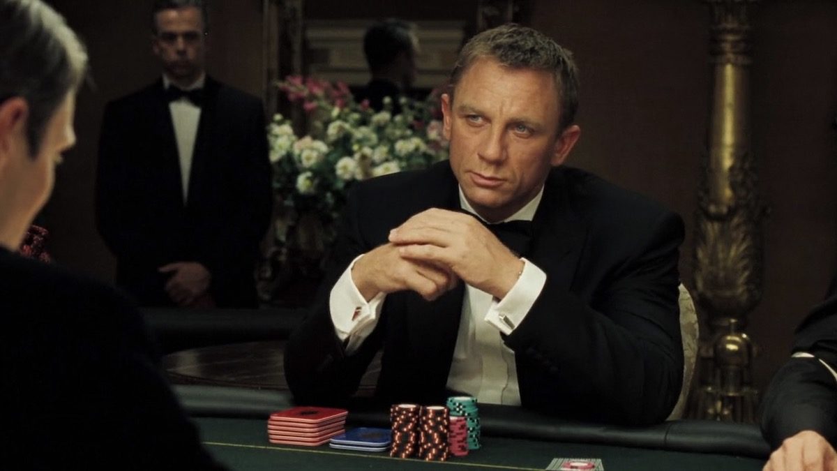 Daniel Craig as Bond in Casino Royale, wearing a tux and sitting at a poker table.