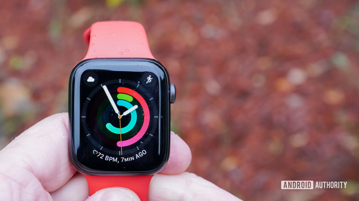 A user holds an Apple Watch SE with a red band, one of our top picks for the best cheap smartwatches you can buy.