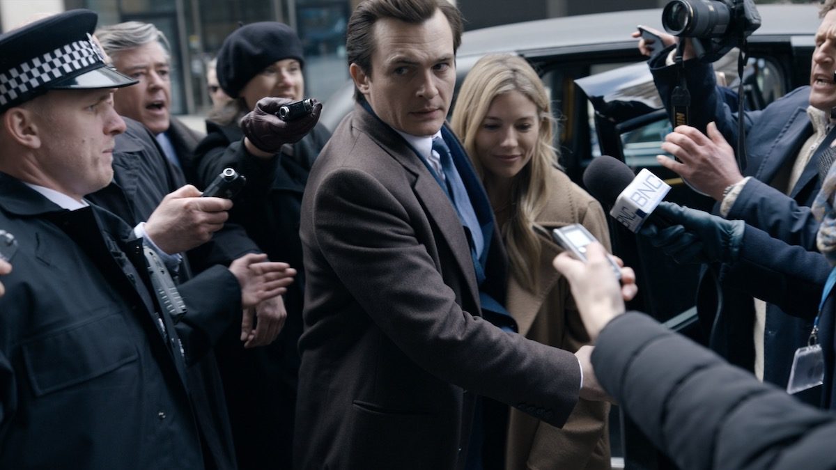 Rupert Friend and Sienna Miller are swarmed by reporters as they exit a car in Anatomy of a Scandal