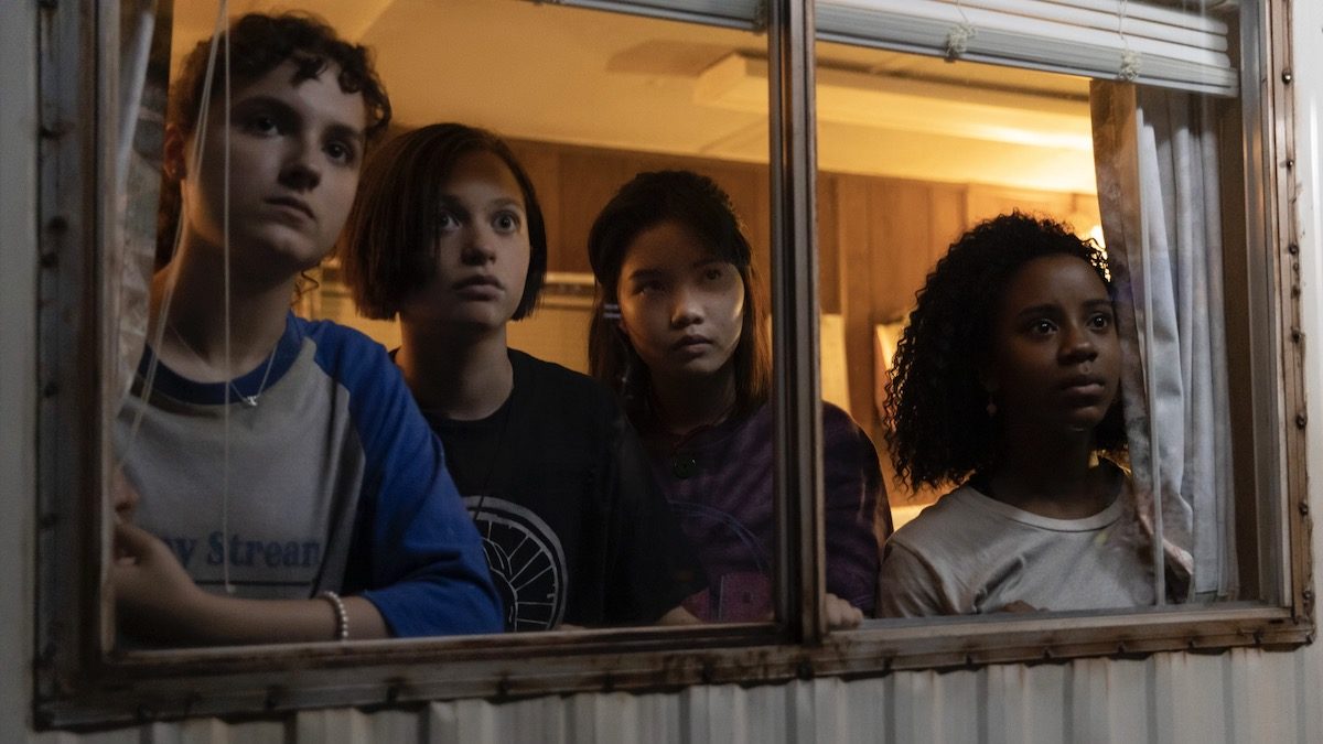 Four girls stand at a window in Paper Girls