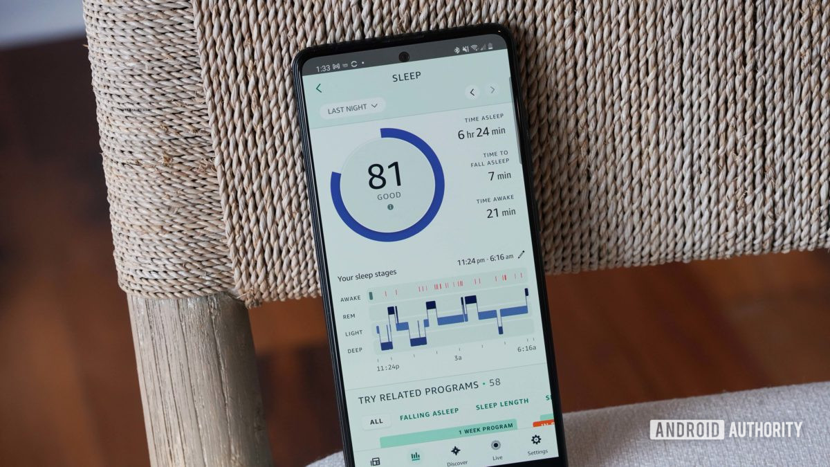 A Samsung Galaxy A51 displays sleep data in the Amazon Halo App on a beige chair.