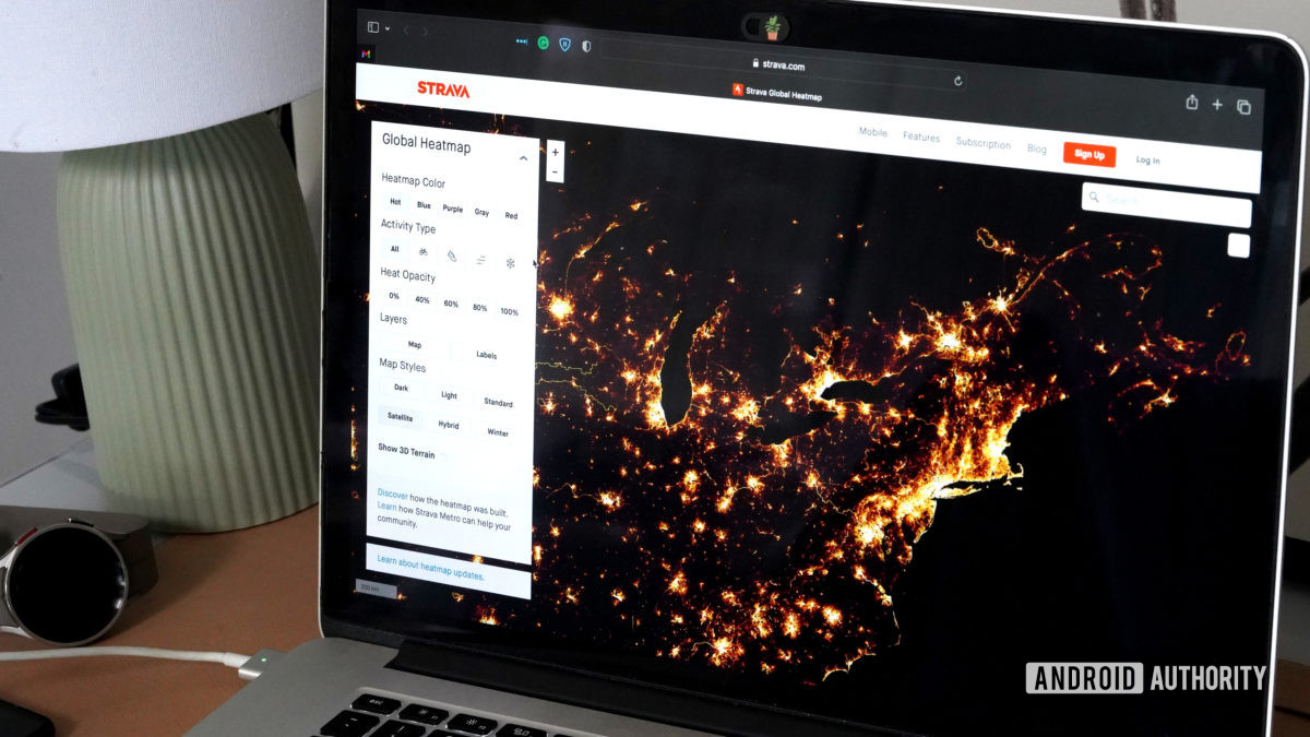 A laptop displays the Strava Global Heatmap.