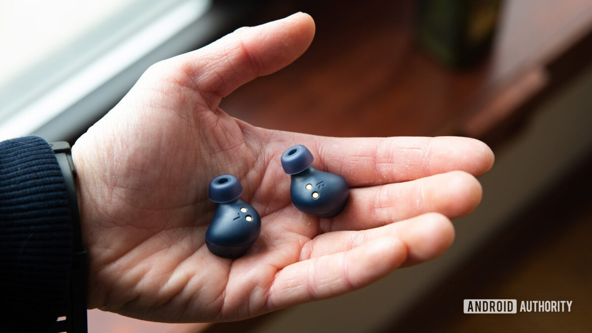 A hand holds the Jabra Elite 4 wireless noise-cancelling earbuds.