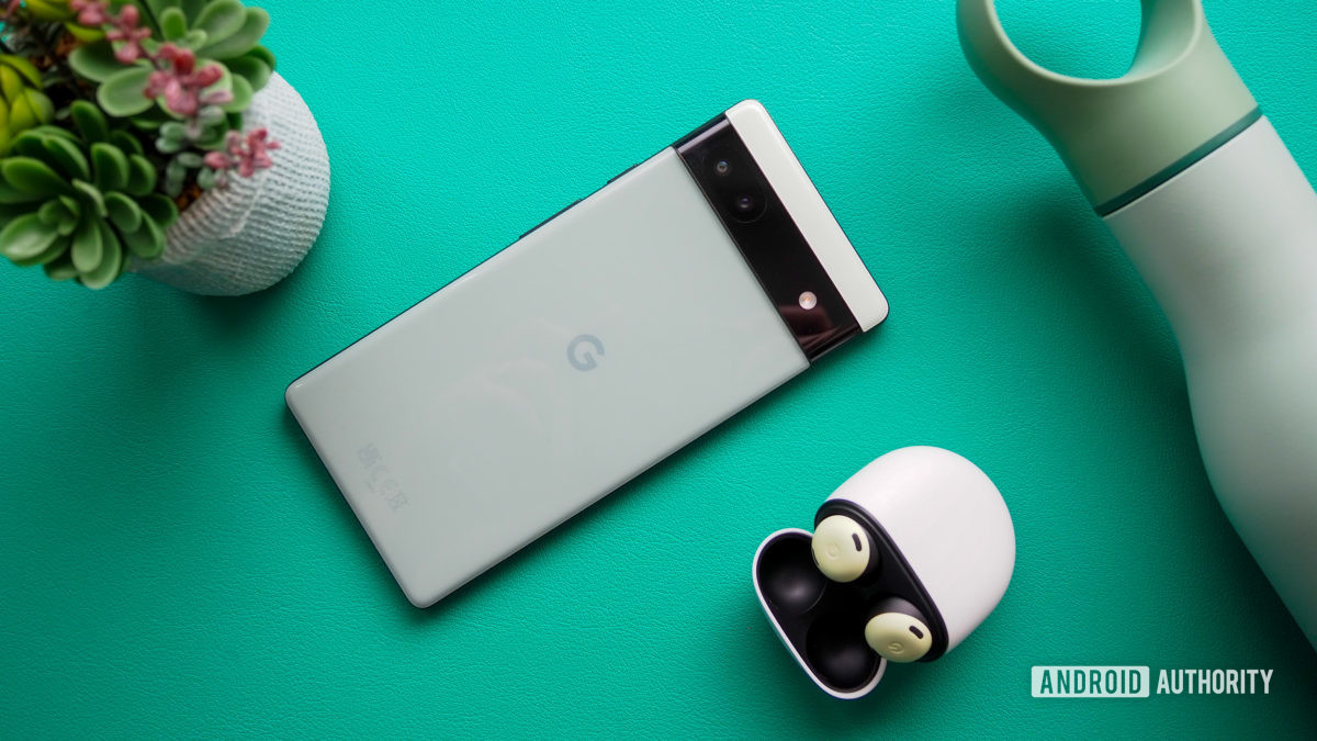 Google Pixel 6a in Sage color, seen from the back, next to Pixel Buds Pro, on a turquoise background