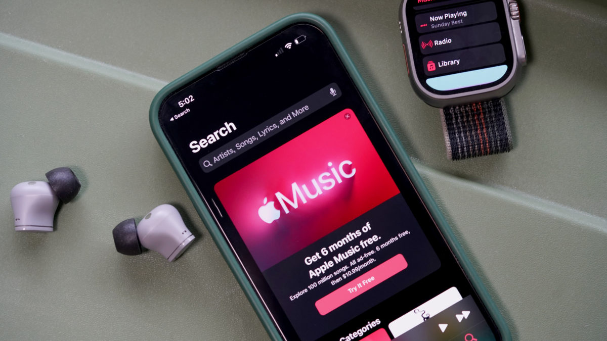 An iPhone displaying an ad for Apple Music rests alongside an Apple Watch Ultra.
