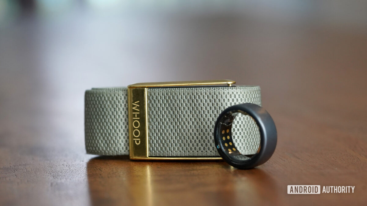 An Oura Ring 3 and Whoop 4 rests side by side on a wooden surface.