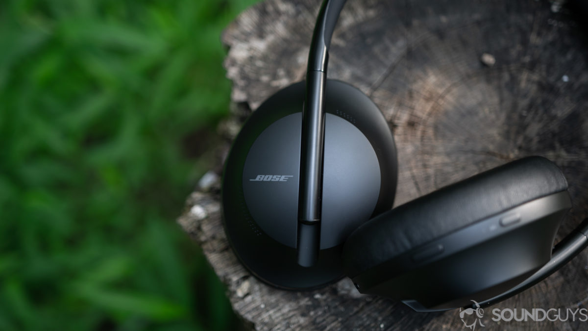 The Bose Noise Cancelling Headphones 700 lying on a tree stump outdoors.