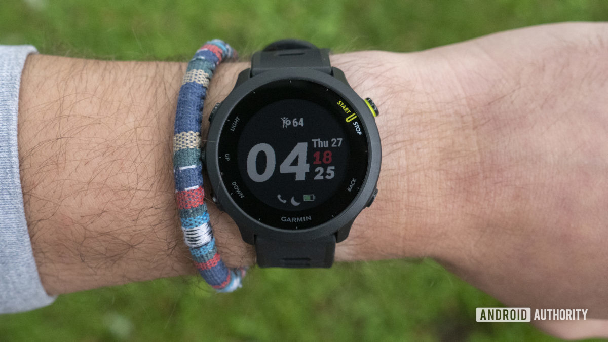 A Garmin Forerunner 55 on a user's wrist display the device's watch face.