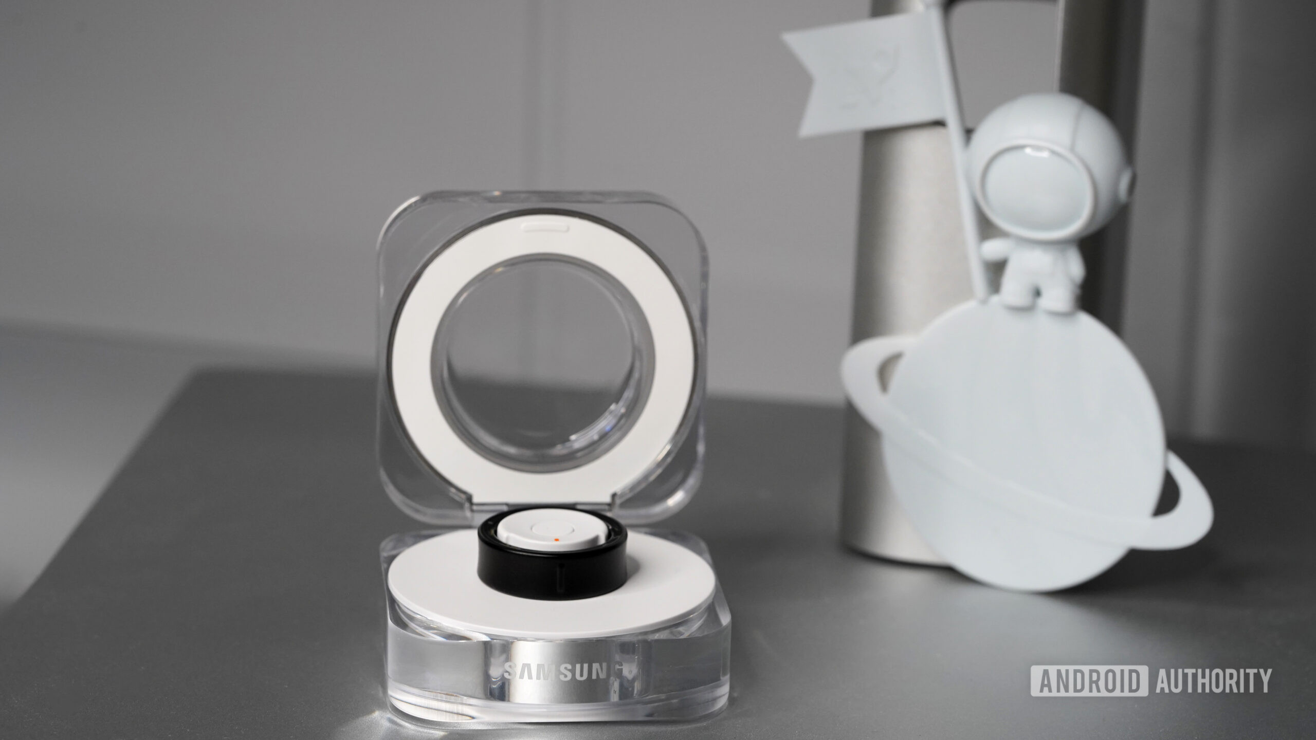 A Samsung Galaxy Ring rests in its open clamshell charging case.