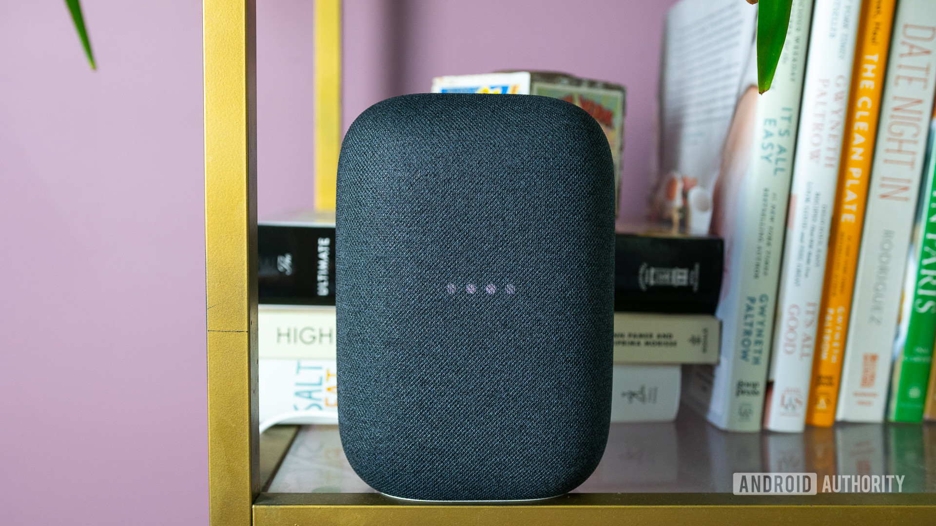 Pictured is the gray Google Nest Audio on a bookshelf with the lights blinking.