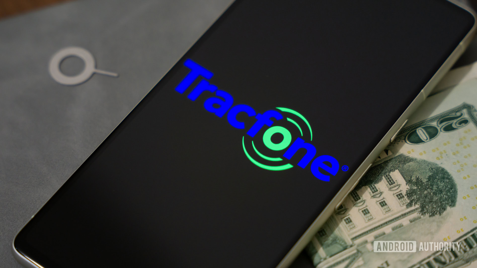 Tracfone logo on smartphone, next to cash and SIM ejector tool (1)