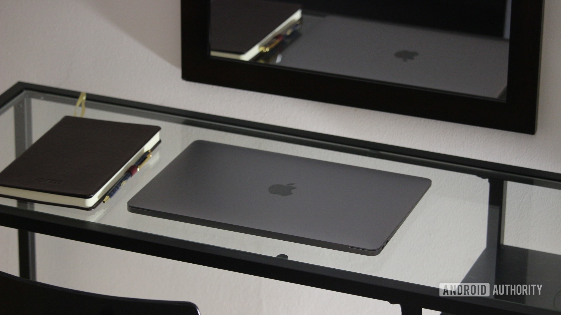 Apple MacBook Air M1 on glass desk next to a notepad