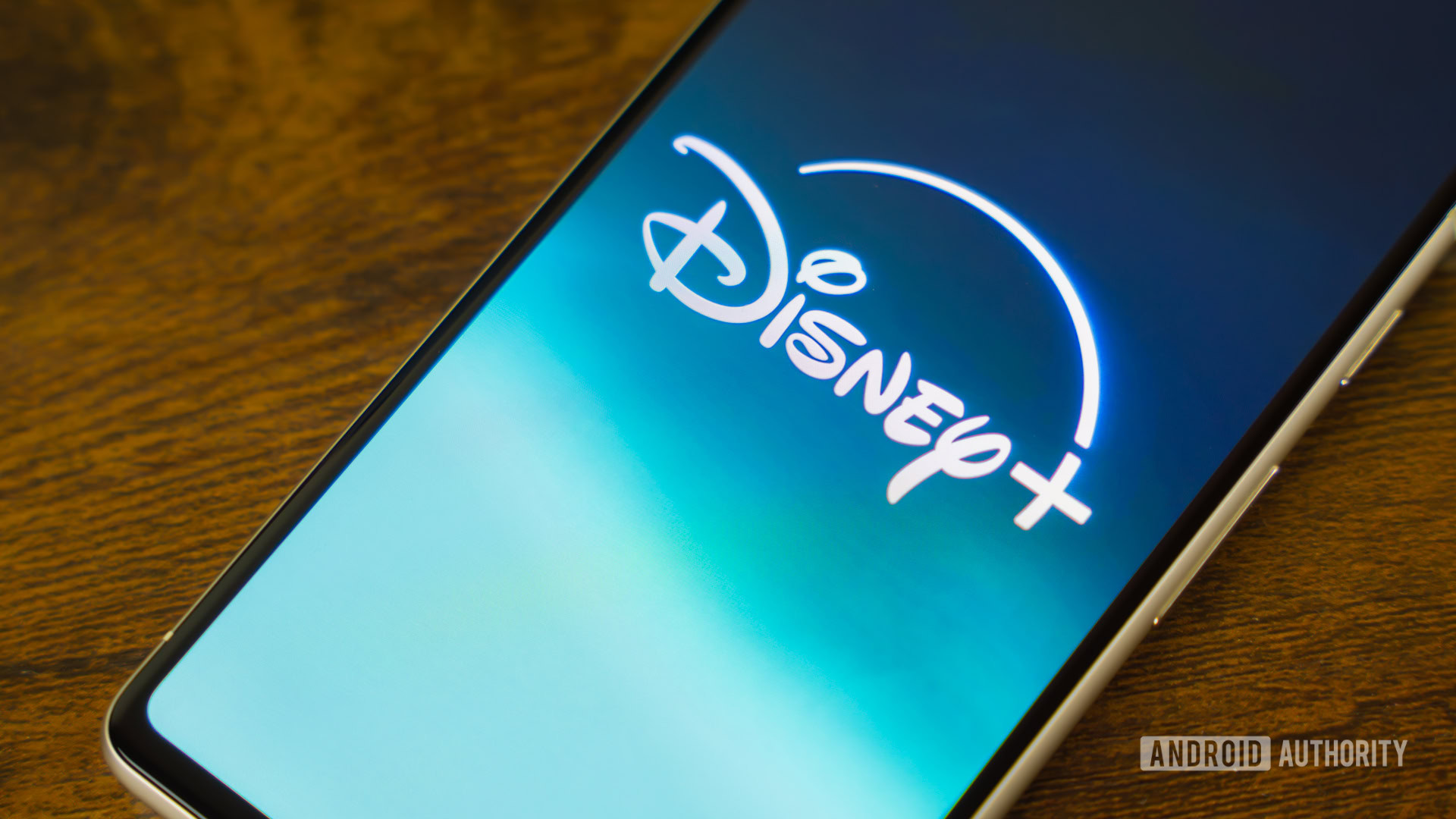 Disney Plus logo on smartphone laying on side table stock photo (4)