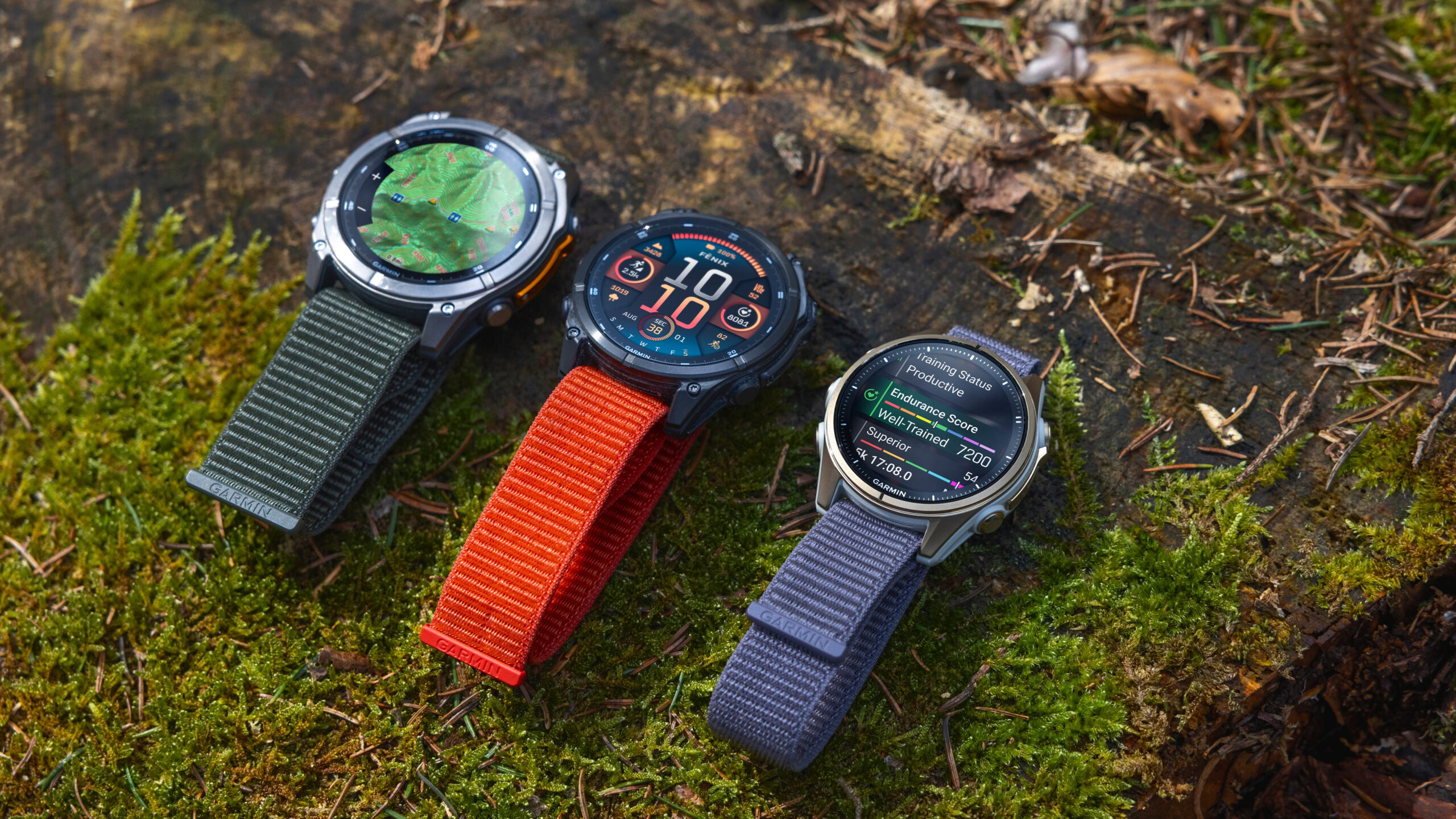 Three Garmin fenix 8 devices rest on a mossy surface.