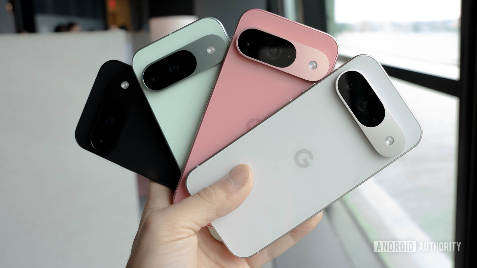 Google Pixel 9 in four colors all held in one person's hand in a fan shape