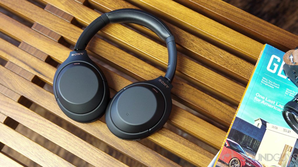 Sony WH-1000XM4 headphones next to magazines on a wood bench