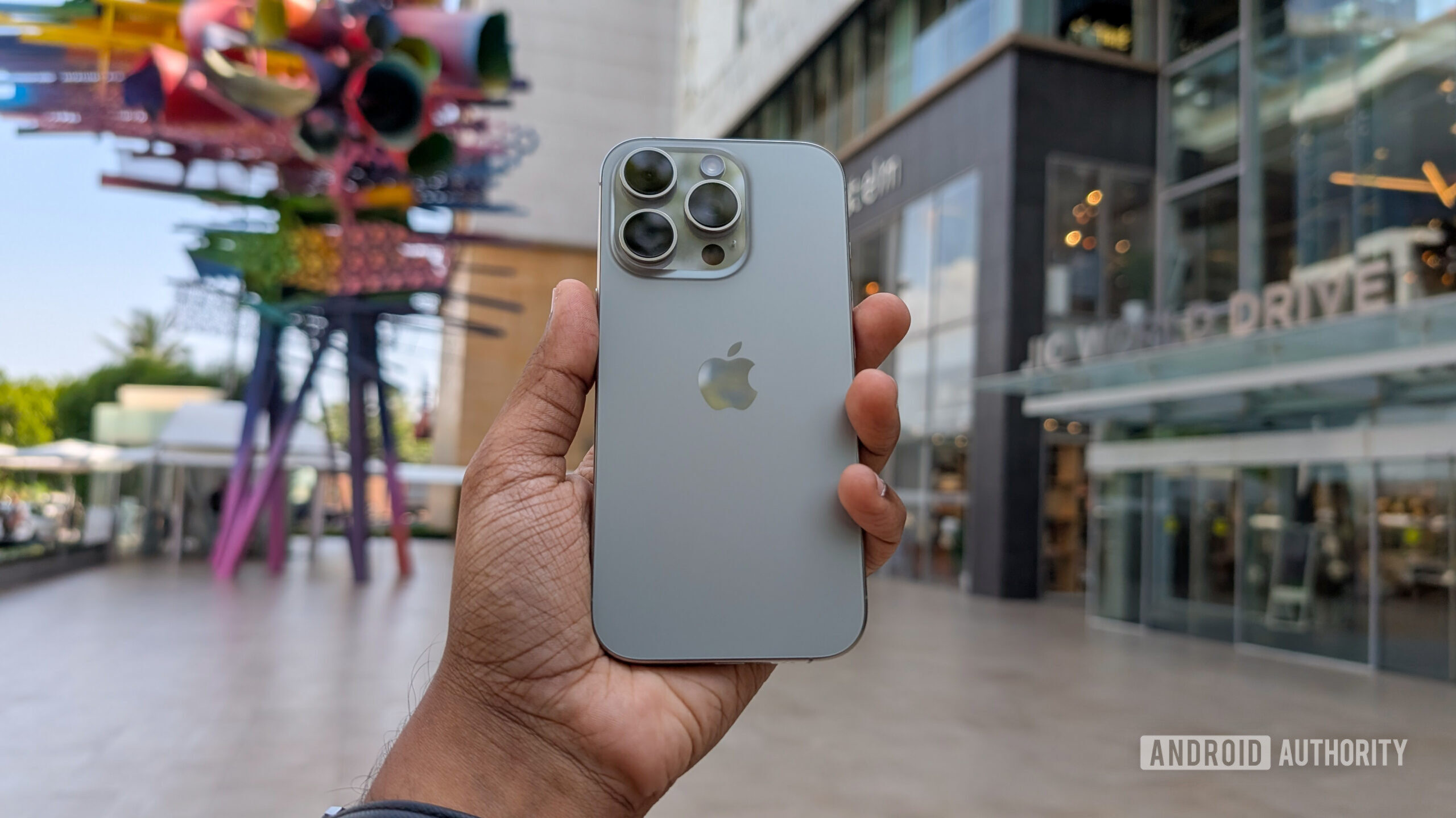 Apple iPhone 16 Pro in Natural Titanium color, held out in hand