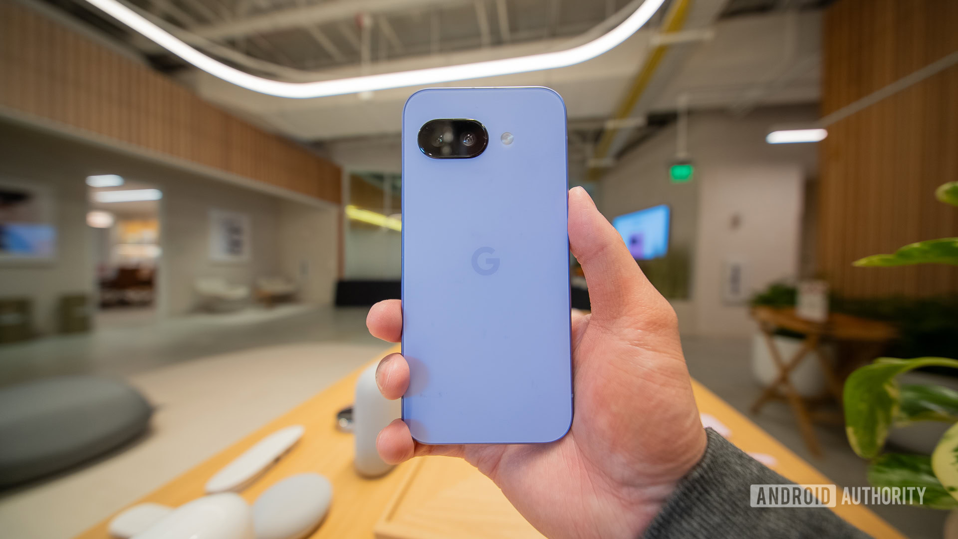 A user holds a Google Pixel 9a in Iris.