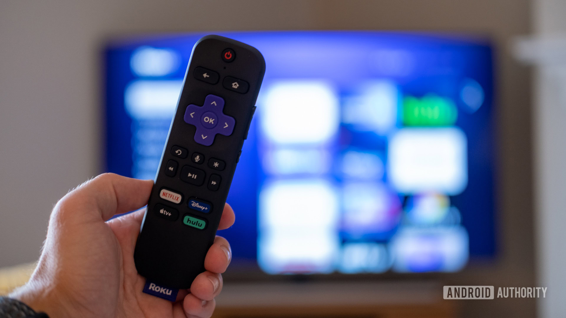 roku streaming stick 4k remote in front of tv The Roku Streaming Stick 4K remote in front of a TV