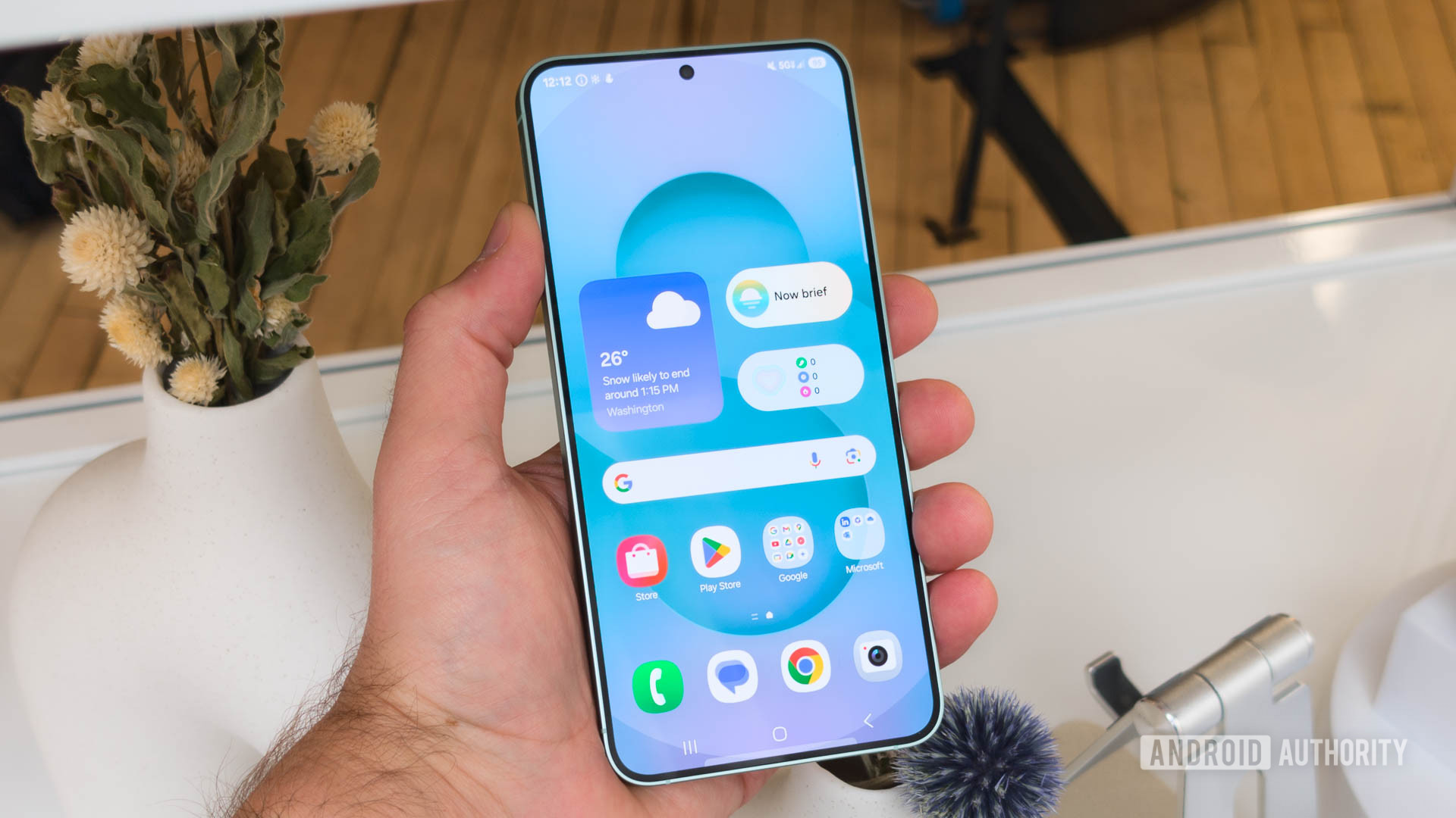 Samsung Galaxy S25 in hand showing home screen