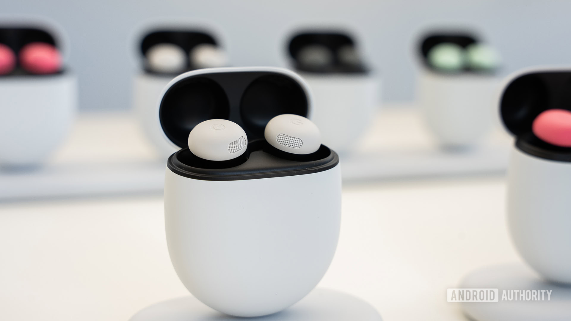 Google Pixel Buds Pro 2 in Porcelain color standing upright in case with other Pixel Buds Pro 2 cases behind it