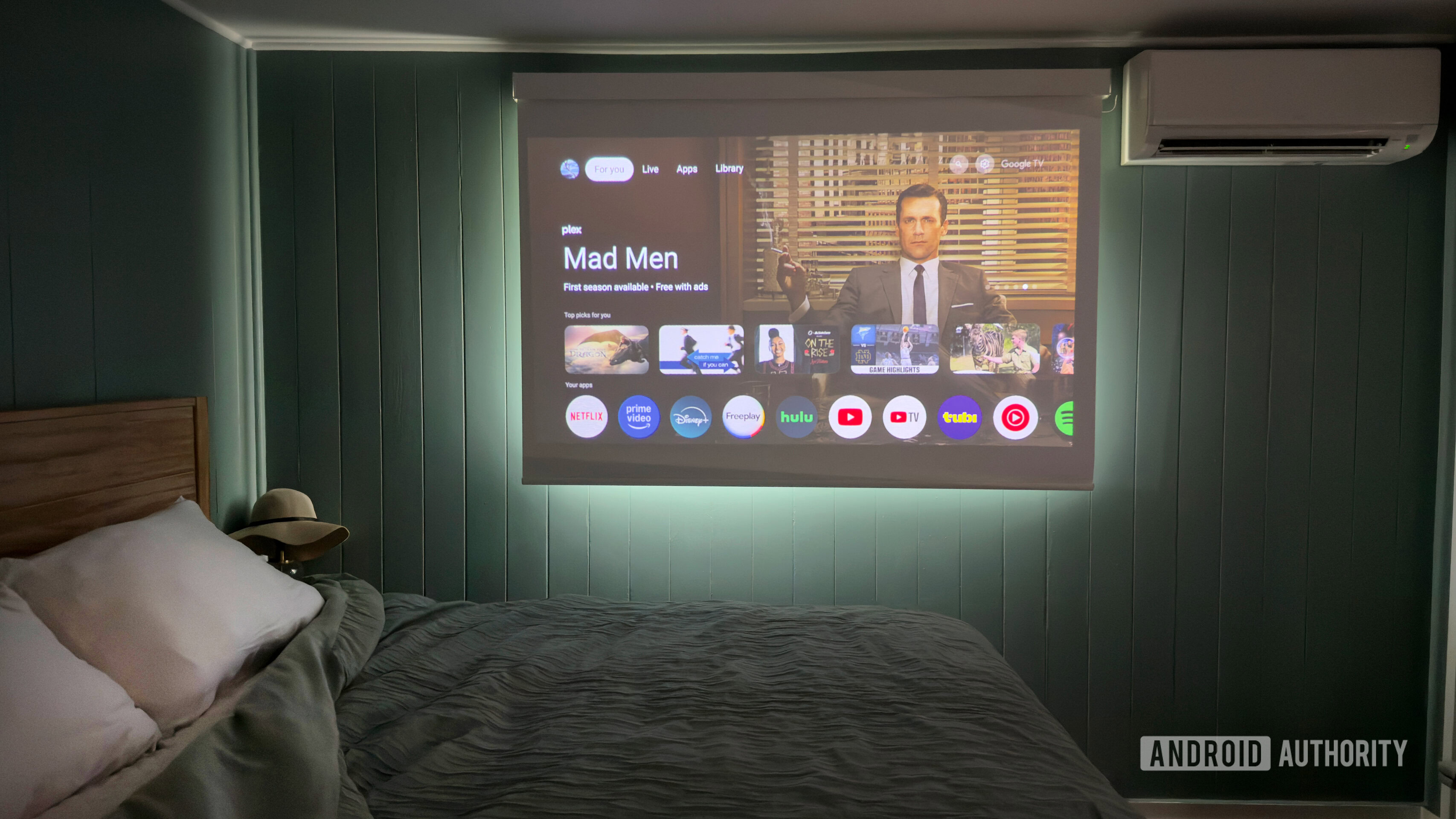 An XGIMI Mogo 4 projects Google TV over a bed.