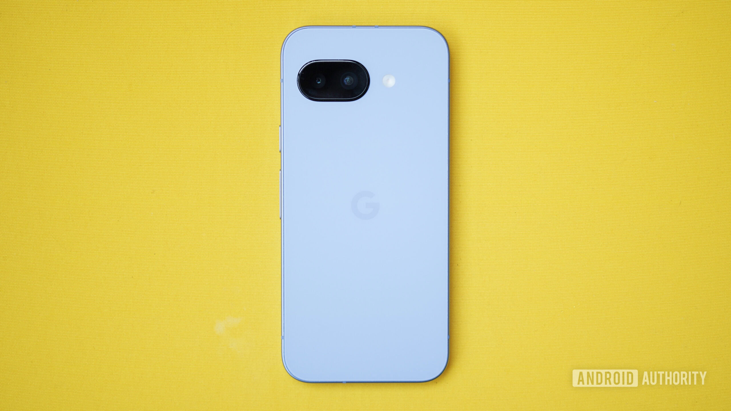 The Google Pixel 9a lying face-down on a yellow cushion.