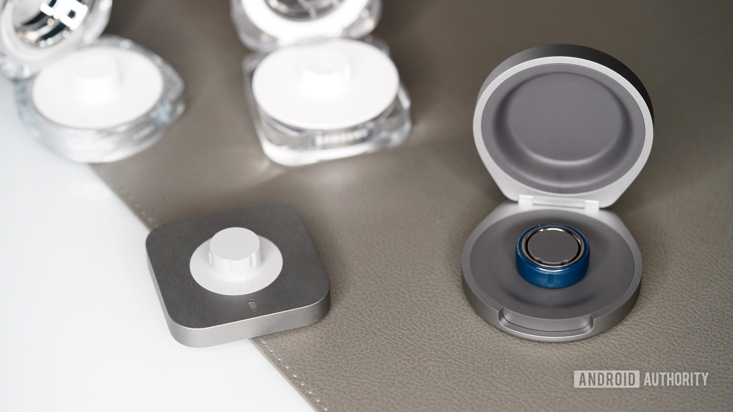 An Oura Ring Charging Case 4 rests among alternative chargers.