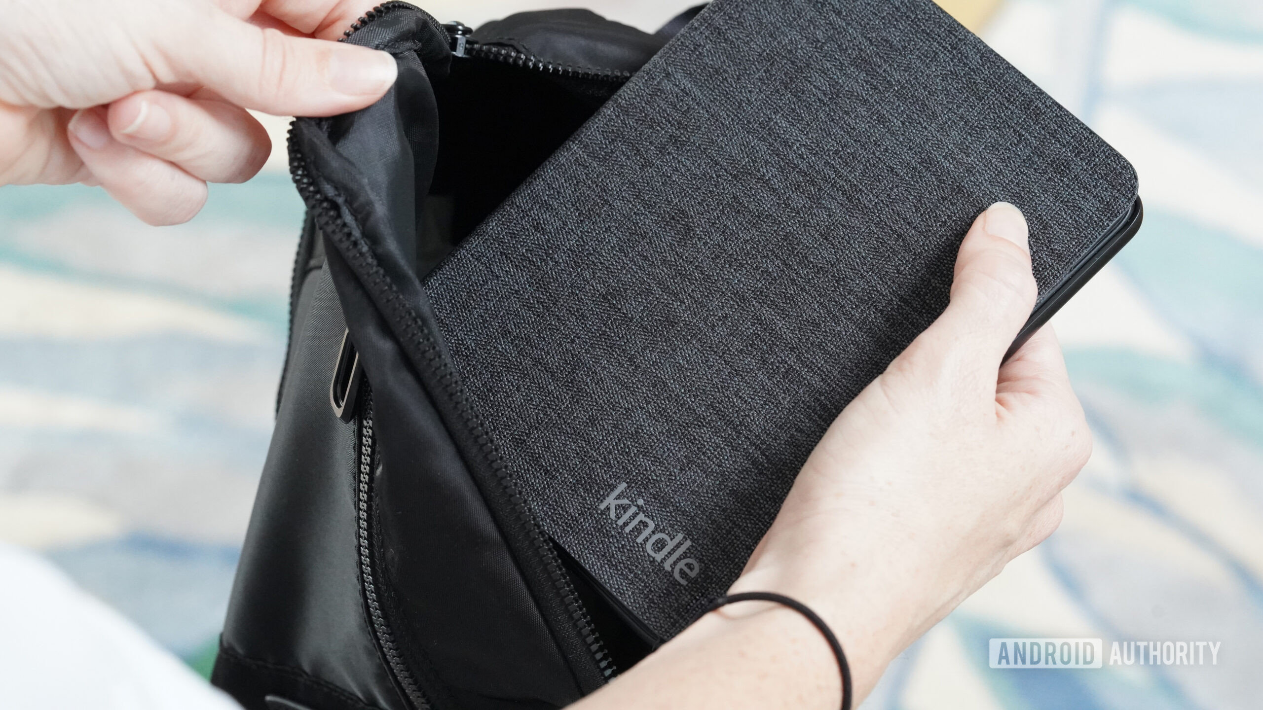 An Amazon Kindle user stows their device in a small bag.
